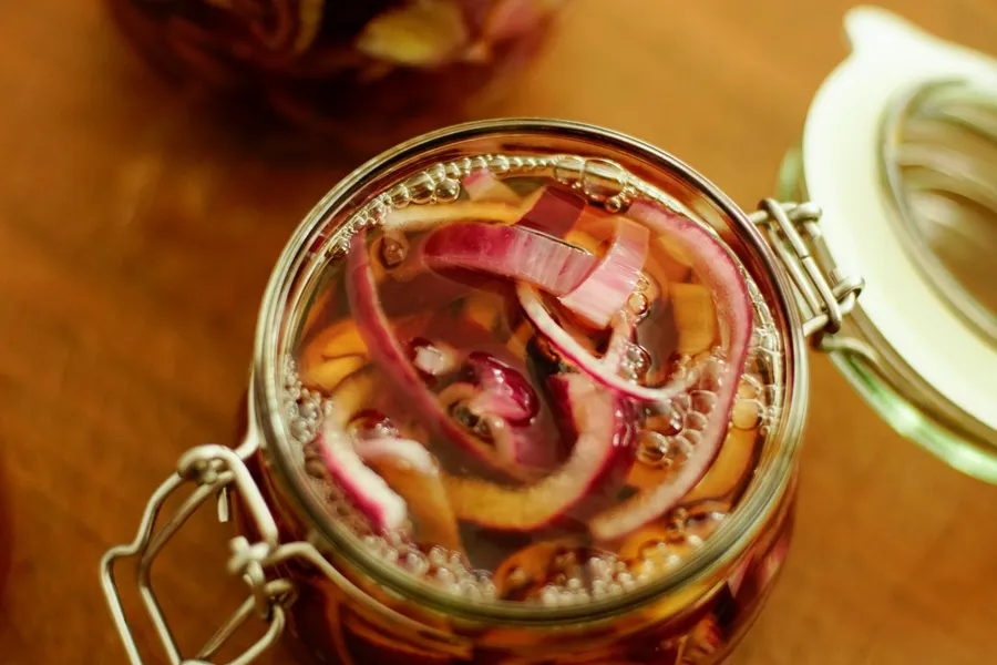 Clear glass jar filled with pink pickled red onions