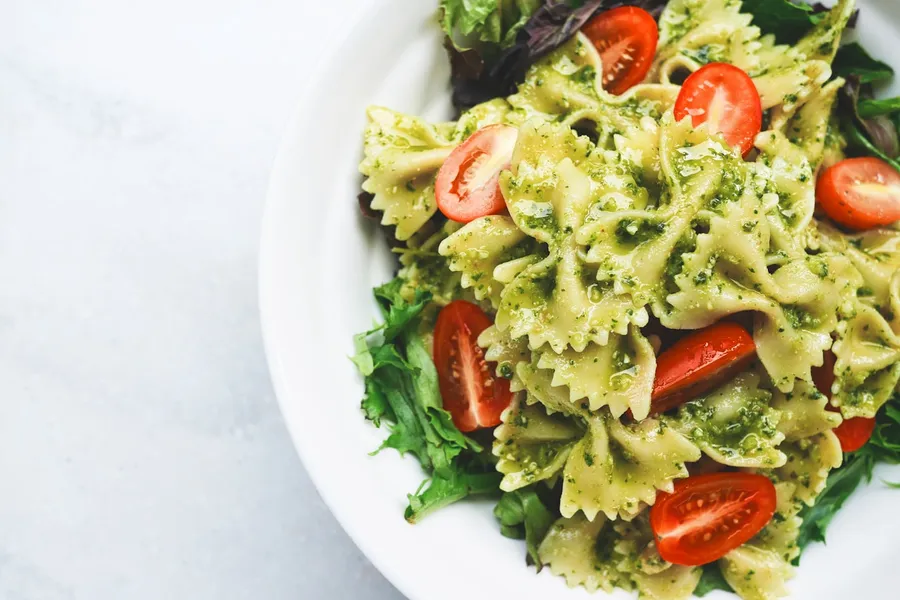 Simple pantry pasta with tomatoes, herbs, and parmesan in a shallow bowl
