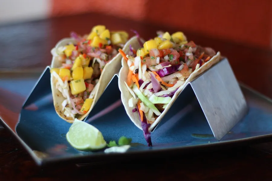 Fish tacos with cabbage slaw, mango salsa, and lime on a plate